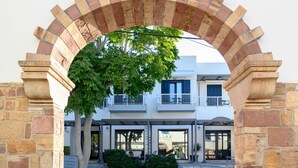 An entrance with a stone archway leading to a building with a balcony and a tree. - Ilioxenia Studio & Apartments (Chios)