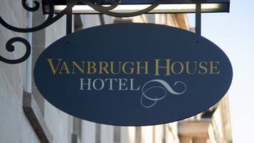 A sign for Vanbrugh House Hotel with a classic design, hanging from a metal bracket.