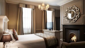Una habitación de hotel con cama, televisión, chimenea y un espejo decorativo.