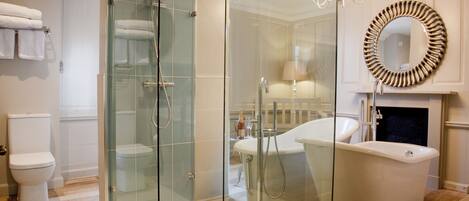 A modern bathroom with a glass-enclosed shower, a freestanding bathtub, and a round mirror above the sink.