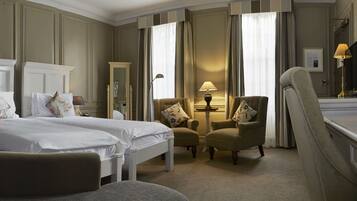 Een hotelkamer met twee bedden, een bureau, een stoel, een lamp en een spiegel.