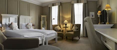 Une chambre d’hôtel avec deux lits, un bureau, une chaise, une lampe et un miroir.