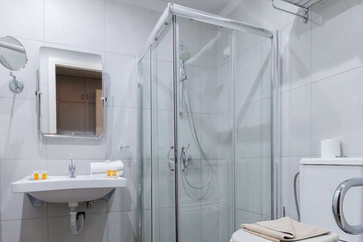 A modern bathroom with a glass-enclosed shower, a sink with a mirror, and a toilet.