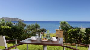 Taula preparada amb gots, una gerra i un plat de galetes, amb vista a un paisatge marí i una illa a la distància.
