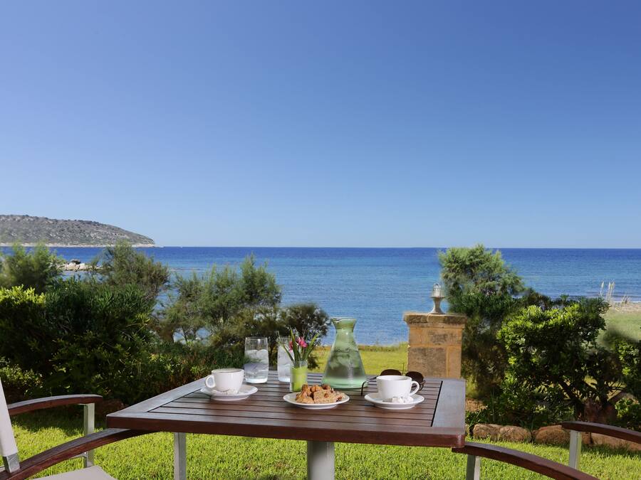 A table set with cups, a pitcher, and a plate of cookies, overlooking a scenic view of the sea and a distant island.