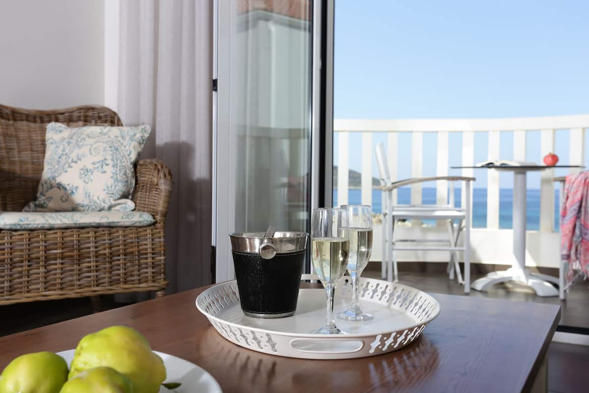 A balcony with a wicker sofa, a white table with a tray holding a bucket, glasses, and a plate of fruit.