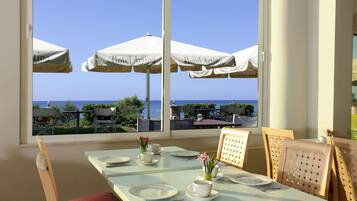 Un comedor con una mesa dispuesta para dos, con vistas panorámicas al mar.
