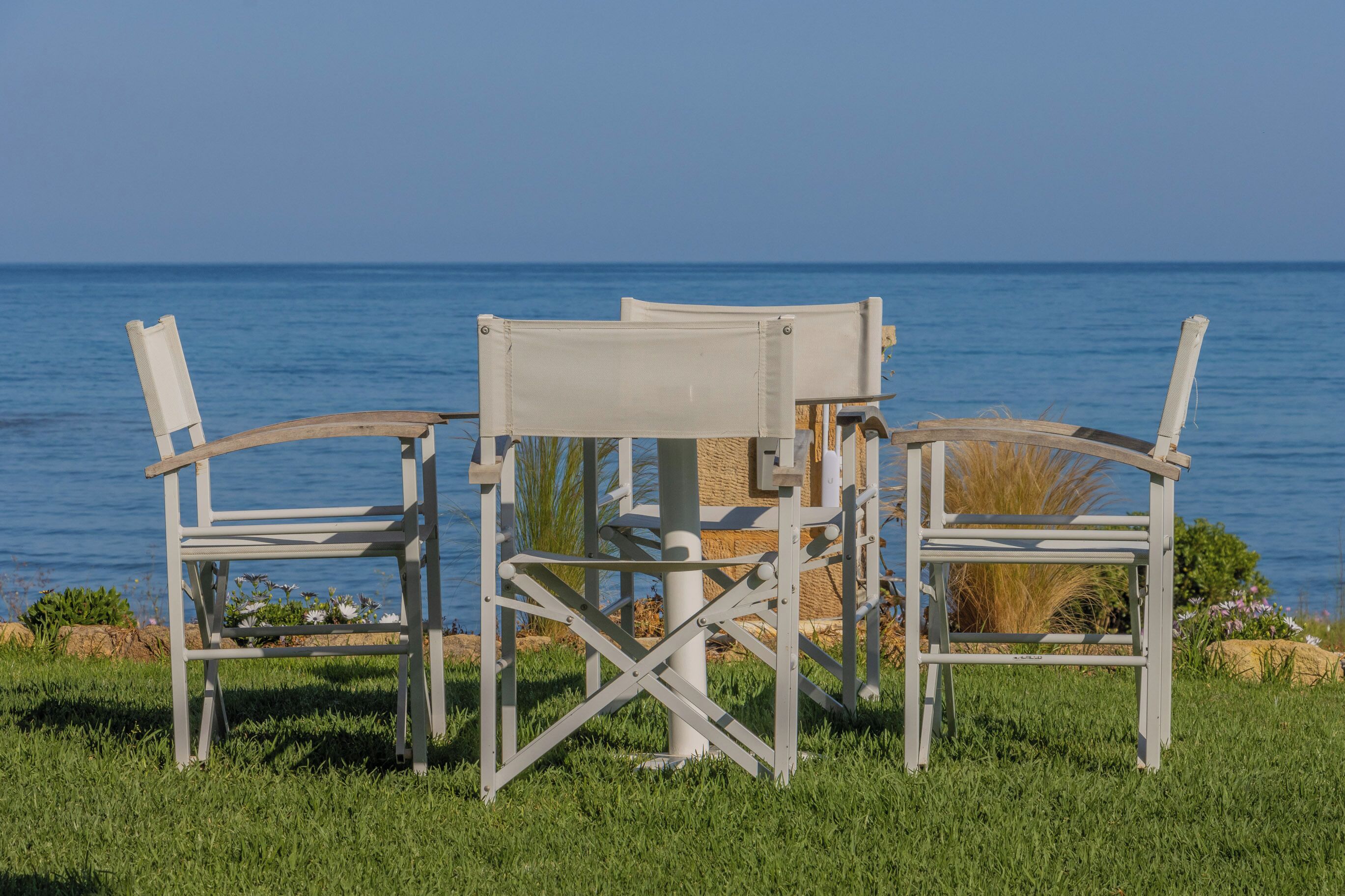 A white outdoor seating area with a view of the sea.
