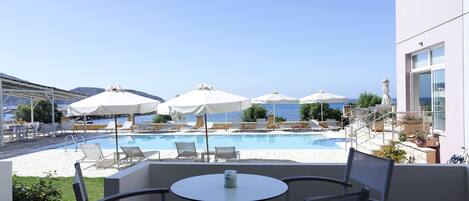 A poolside area with lounge chairs and umbrellas, overlooking a body of water.