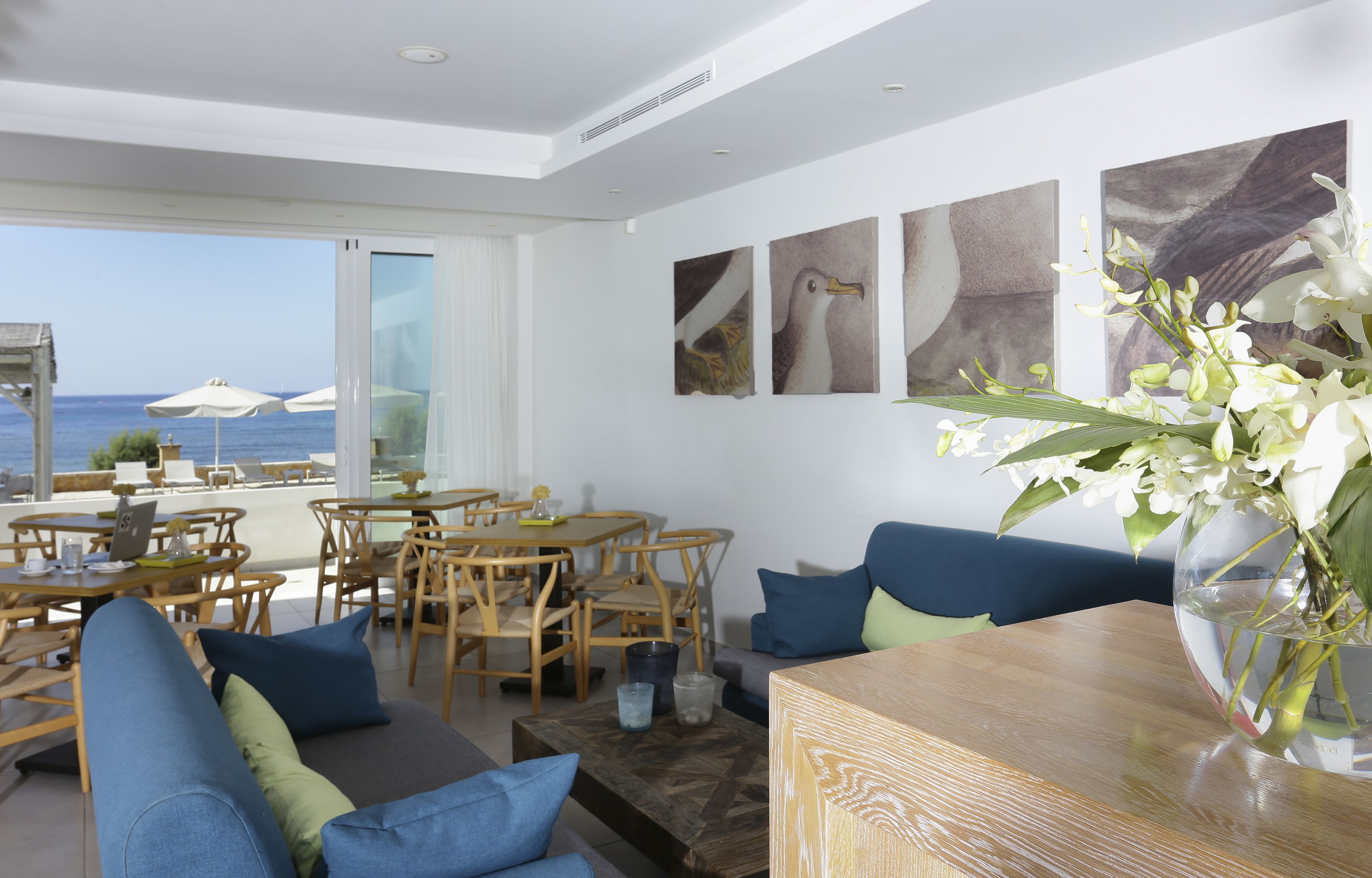 Ein modernes Hotelzimmer mit Balkon und Meerblick, Holzmöbeln und Kunstwerken an den Wänden.
