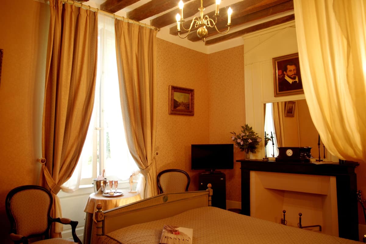 Ein Hotelzimmer mit einem Bett, einem Schreibtisch mit Fernseher, einem Kamin und Vorhängen.