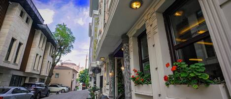 A hotel with a cobblestone street, outdoor seating, and a view of the street.