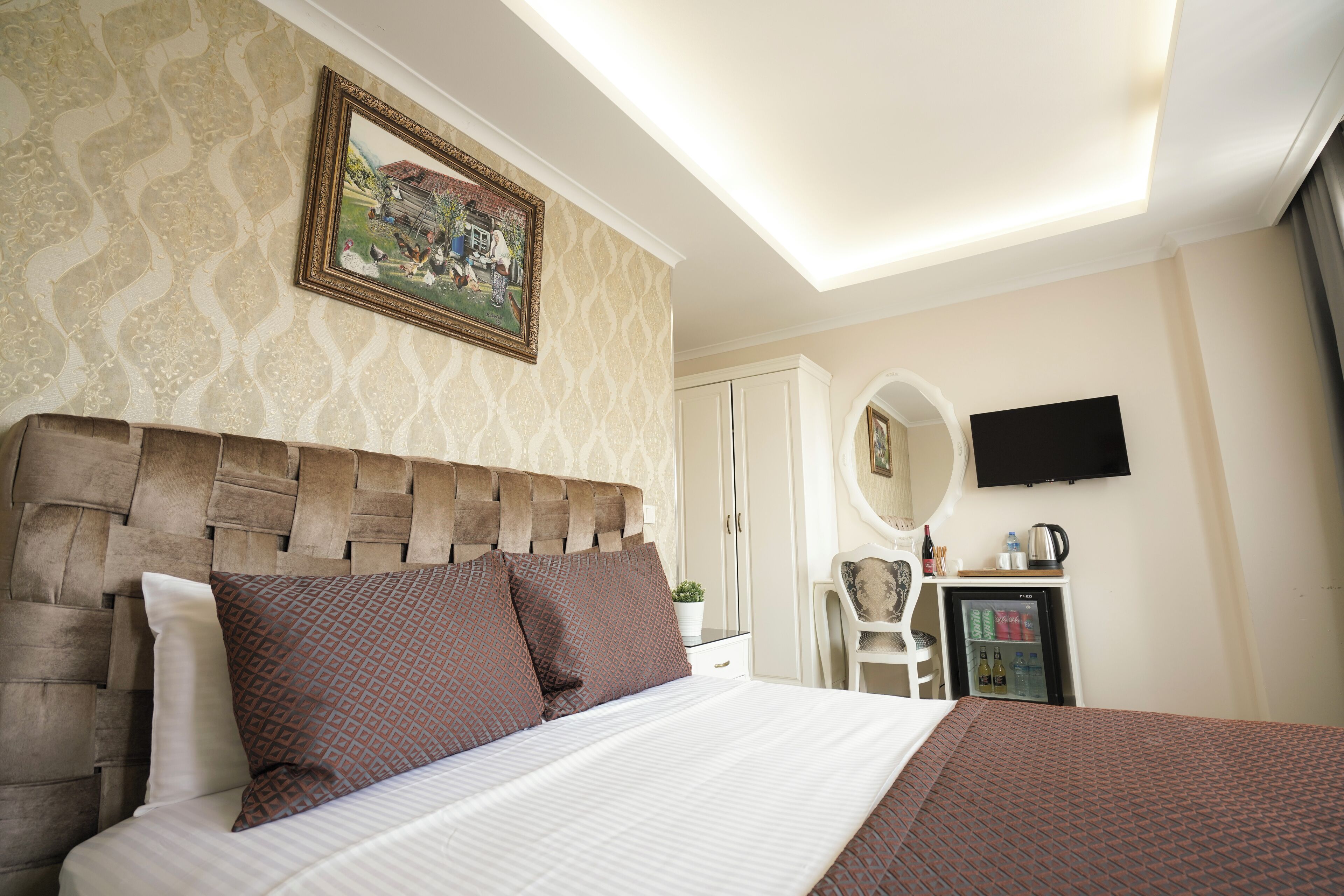 A hotel room with a bed, a television, a small refrigerator, and a desk with a chair.