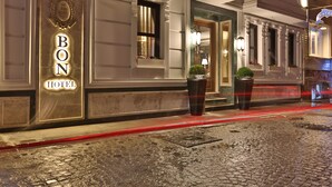 Exterior del Bon Hotel con una fachada clásica, una entrada destacada y dos macetas con plantas en la entrada.