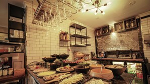 Zona de bufé con diferentes opciones de comida y un refrigerador lleno de bebidas.