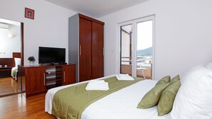 A hotel room with a bed, a TV, a wardrobe, and a balcony with a view. - Apartments Vala (Vela Luka)