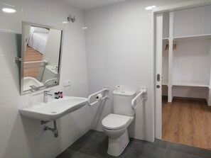 Een moderne badkamer met een wit wastafel, spiegel, toilet en een inloopdouche.