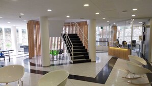 Un hall d’entrée moderne doté d’un escalier central, de coins salon et d’un comptoir d’accueil.