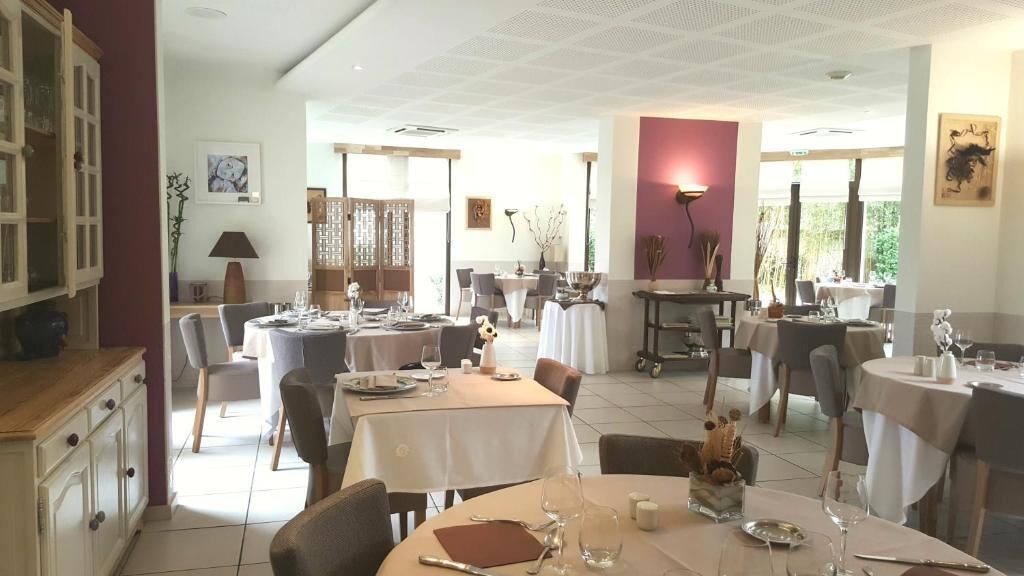 A restaurant with multiple tables set for dining, a bar area, and a view of the outdoors.