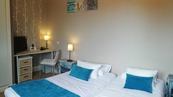 A hotel room with two beds, a desk, a chair, a TV, and artwork on the walls.
