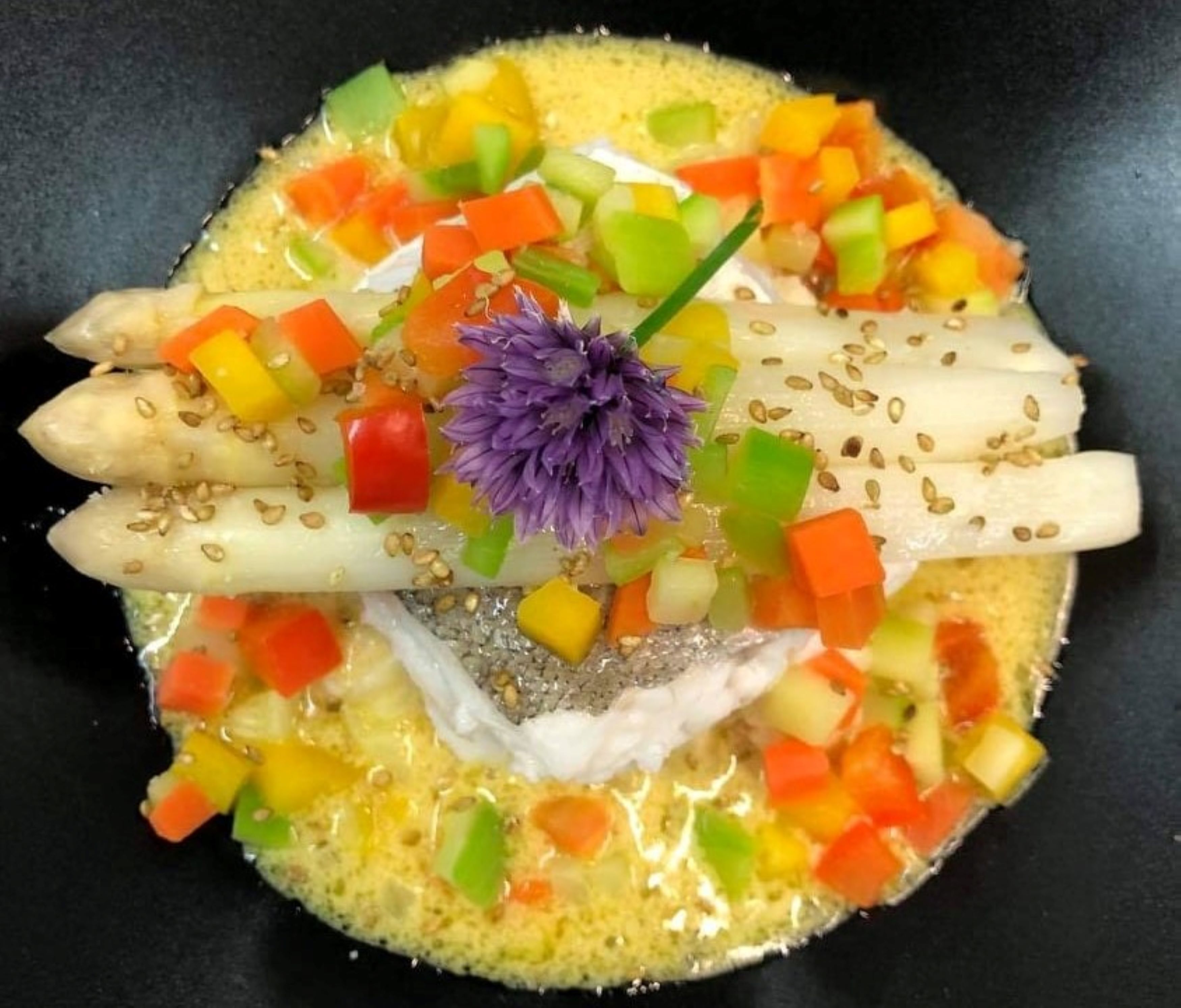 A dish with various vegetables and a purple flower garnish.
