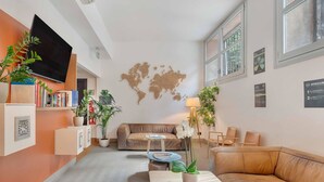 A modern living room with a sofa, a coffee table, and a TV. There are plants and a world map on the wall. - B&B Hotel Milano Sant'Ambrogio (Milan)