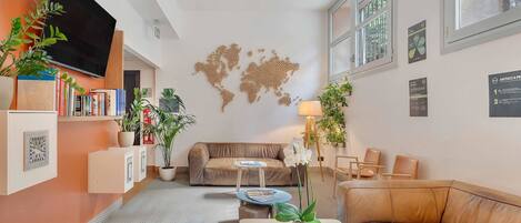 A modern living room with a sofa, a coffee table, and a TV. There are plants and a world map on the wall.