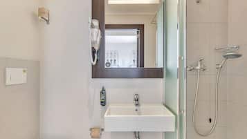 Ein modernes Badezimmer mit Toilette, Waschbecken, Spiegel und Dusche.