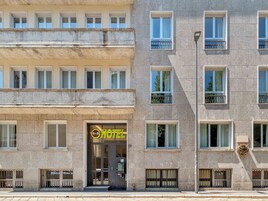 Facciata di un hotel con diverse finestre, un ingresso ben visibile e un tastierino per la sicurezza.