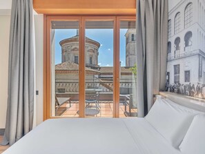 A hotel room with a large bed, a balcony with a table and chairs, and a view of a historic building with a dome and arches. - B&B Hotel Milano Sant'Ambrogio (Milan)