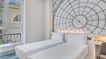 Ein Hotelzimmer mit zwei Einzelbetten, einem großen Fenster und einem außergewöhnlichen Deckenstil.