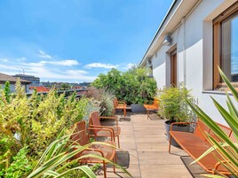Una terrazza sul tetto con posti a sedere all'aperto e vasi di piante.