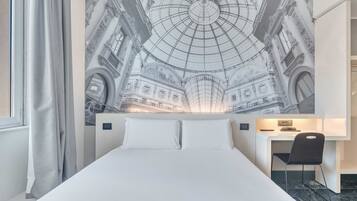 Una habitación de hotel con una cama grande, un escritorio y un mural en la pared de un edificio histórico.