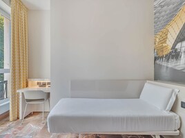 A modern hotel room with a bed, a desk, and a chair.