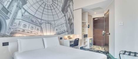 A hotel room with a large bed, a desk, and a chair. There is a mural on the wall depicting a historical building.