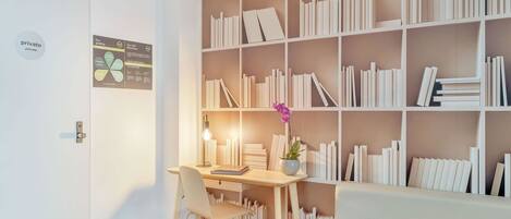 A modern room with a white door, a desk with a chair, a bookshelf, and a white sofa.