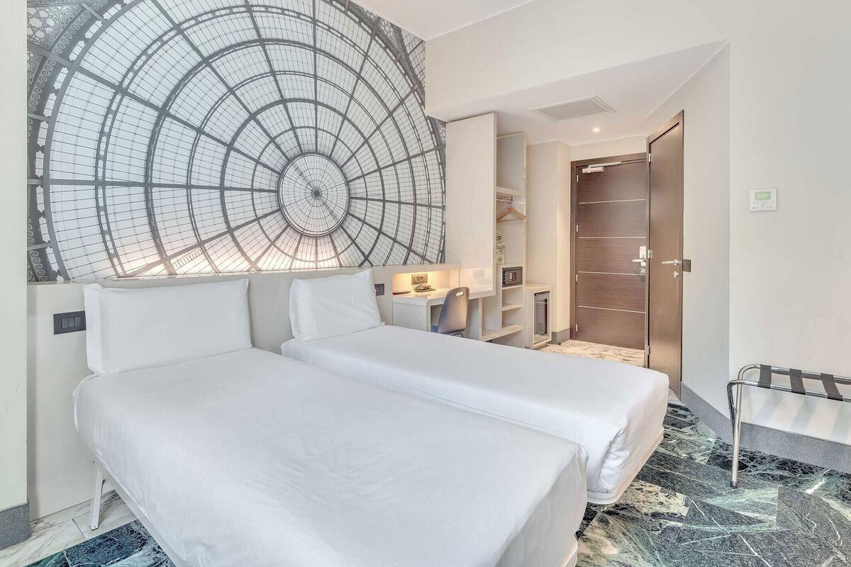 A hotel room with a large skylight, two beds, a walk-in closet, and a bathroom with a modern design.