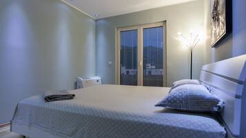 A bedroom with a bed, a bedside table, a lamp, and a window with blinds.