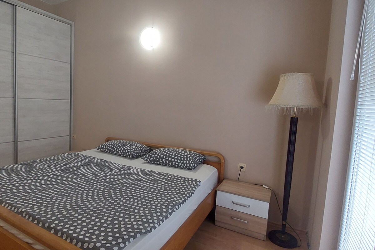 Un dormitorio con una cama, una mesita de noche, una lámpara y un armario.