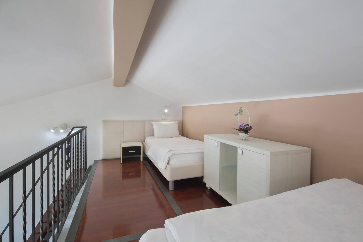 Un dormitorio con cama, mesita de noche, cómoda y barandilla.