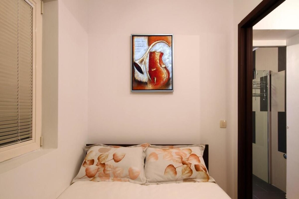 Un dormitorio con cama, un cuadro en la pared y una ventana con persianas.