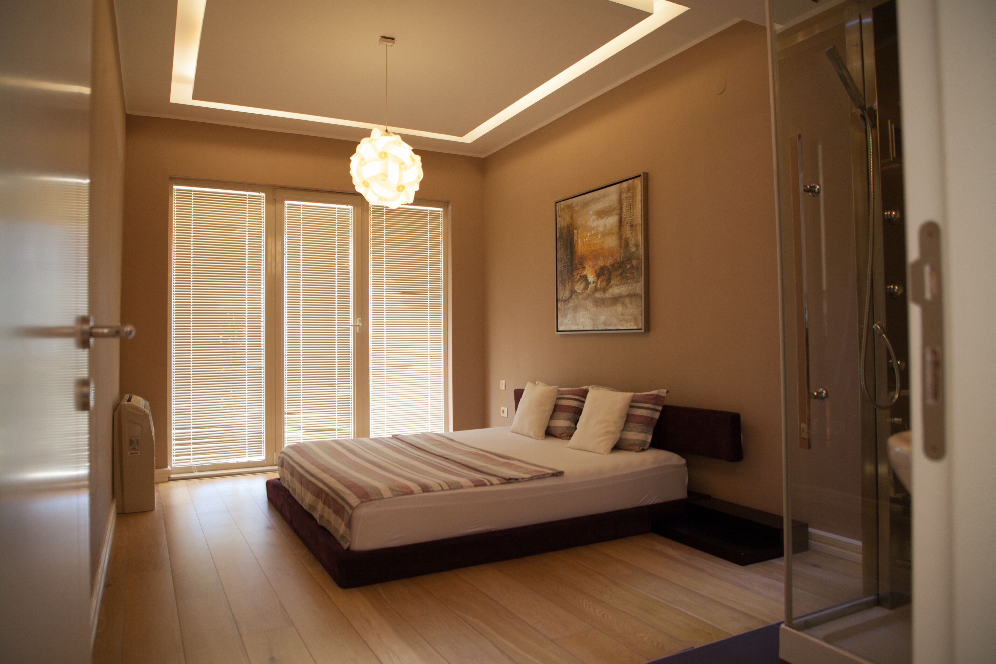 A bedroom with a bed, a shower, and a painting on the wall.
