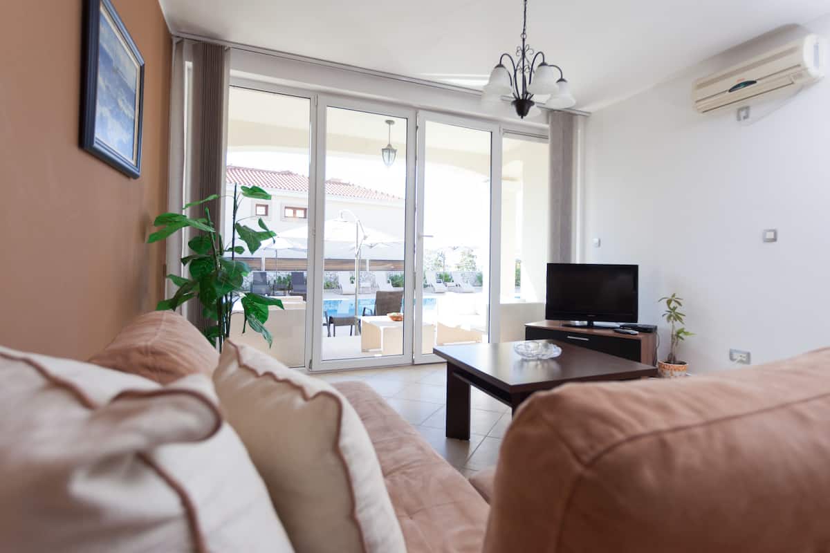 Una sala de estar con un sofá, una mesa de centro, un televisor y una planta en maceta.