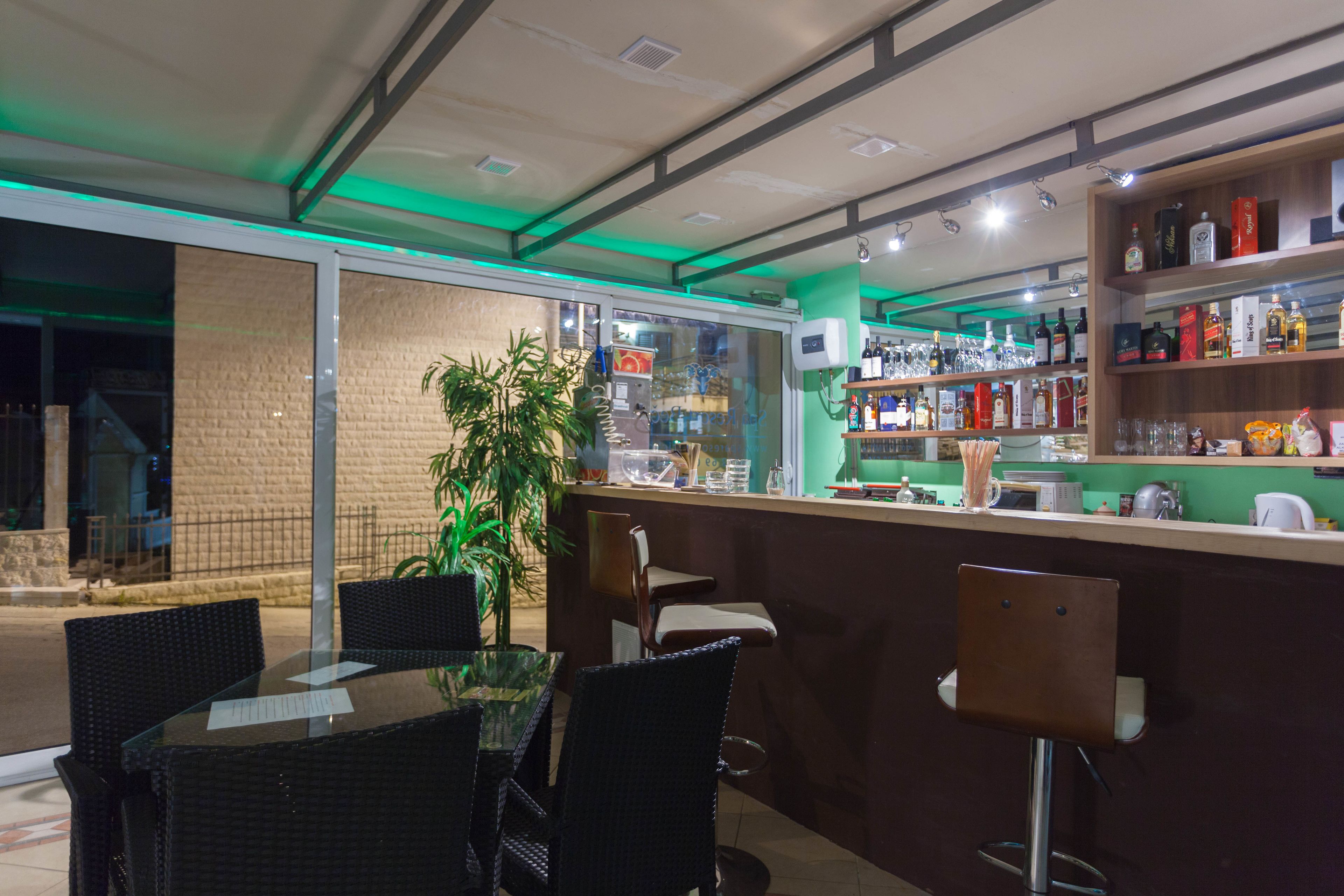 A bar area with a counter, shelves with bottles, and seating with chairs.