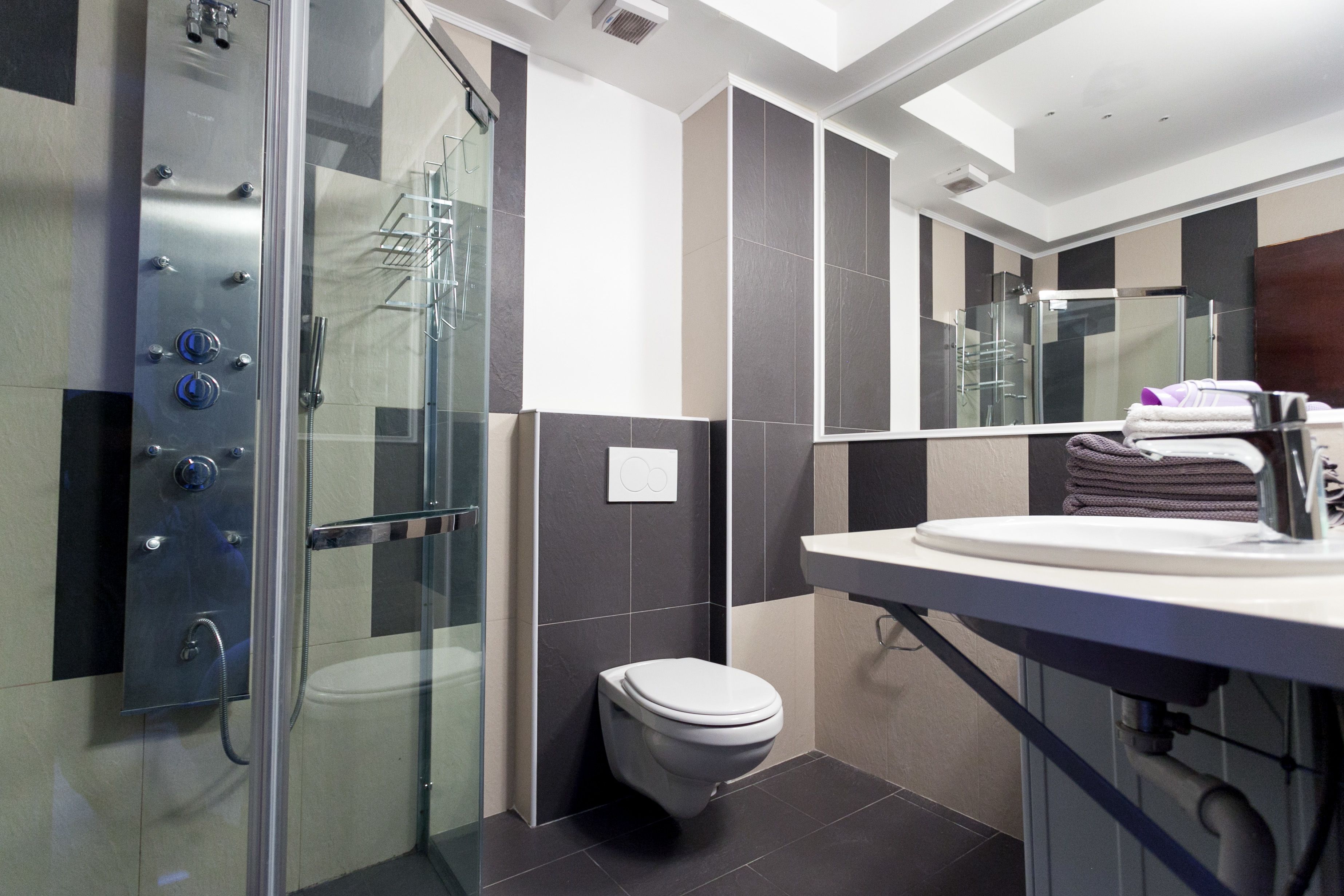 Un baño moderno con ducha de vidrio, inodoro y lavabo con espejo.