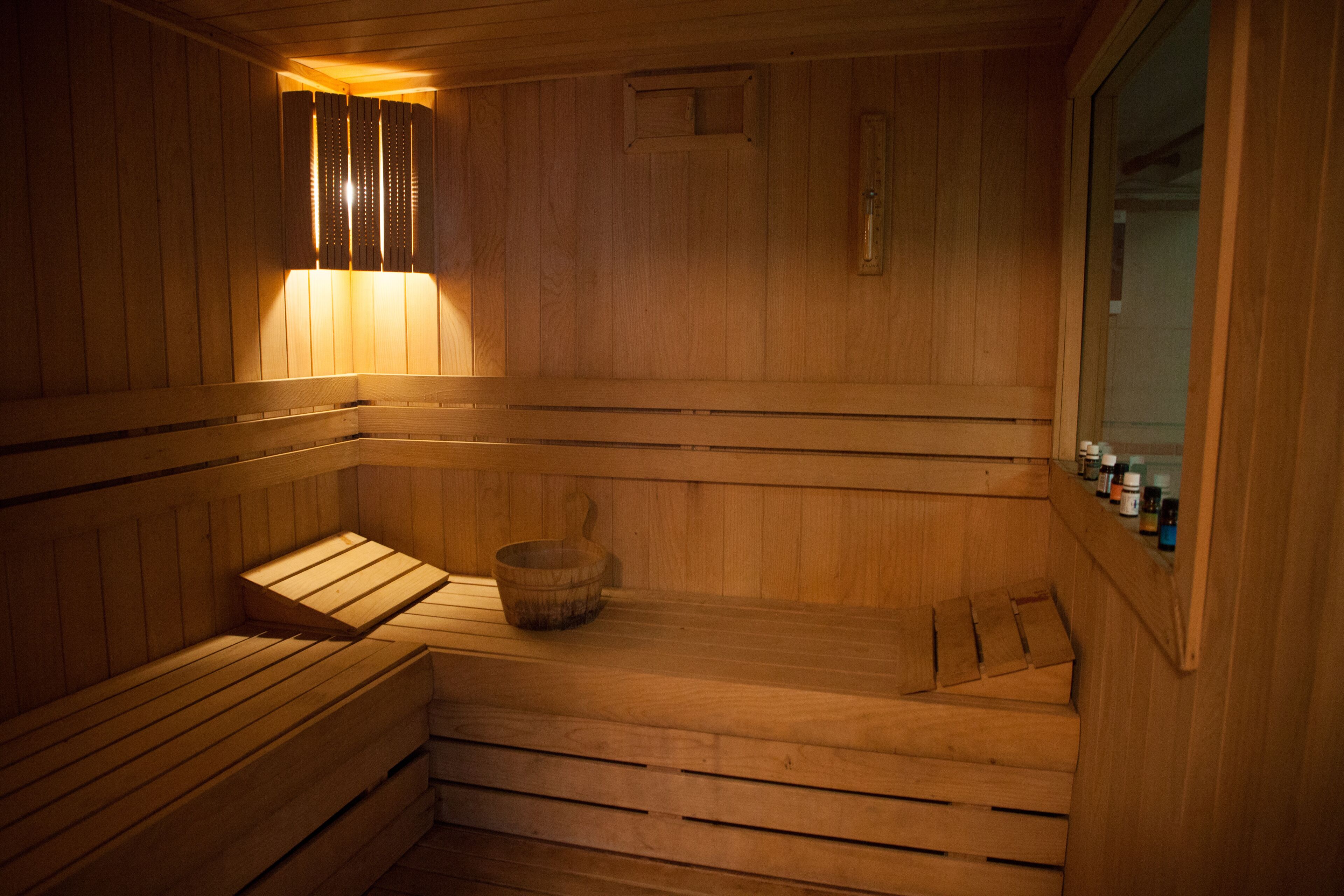 A wooden sauna with benches and a wooden bucket.