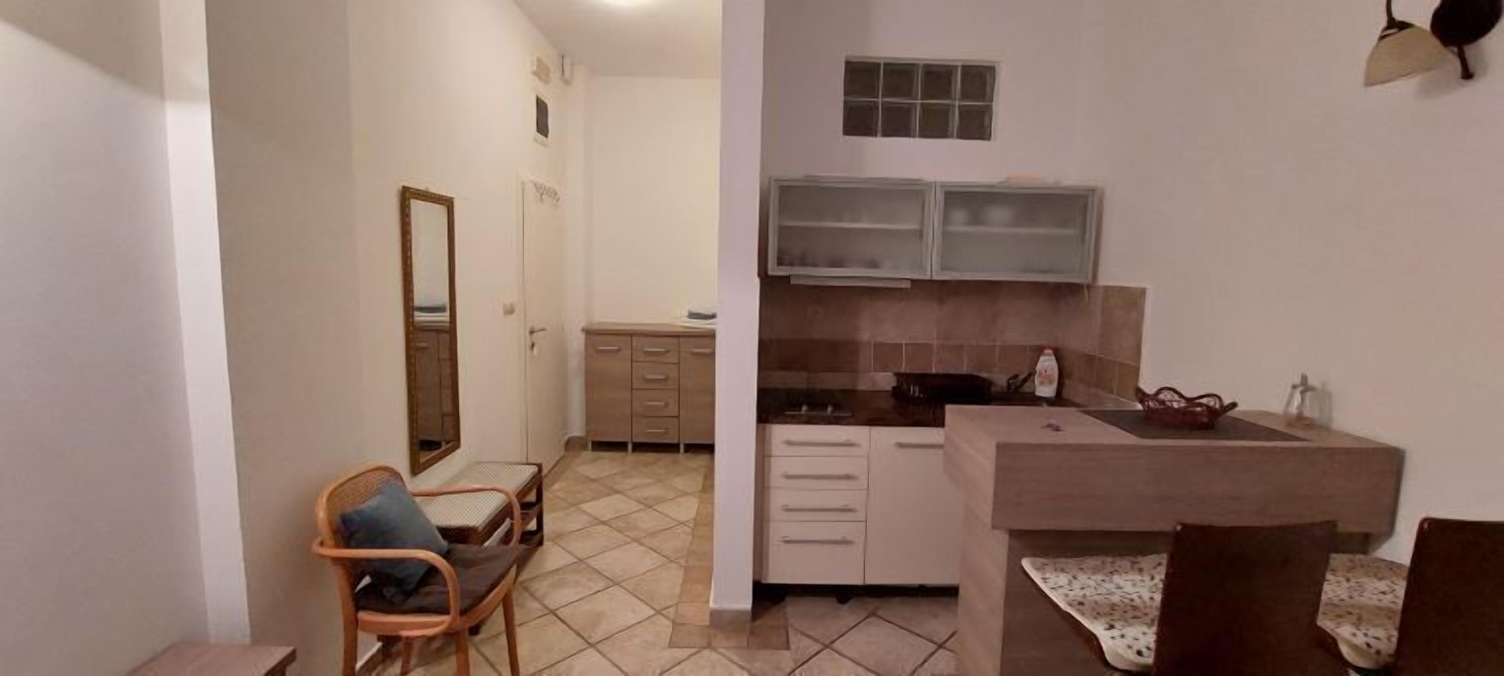 A compact kitchen with a dining area, a small seating space, and a mirror.