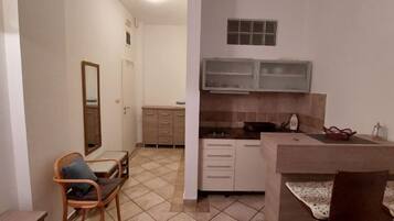 A compact kitchen with a dining area, a small seating space, and a mirror.