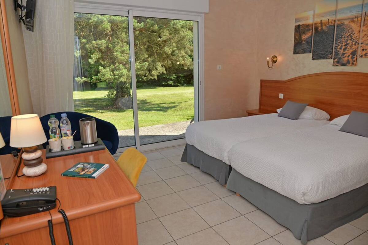 Ein Hotelzimmer mit Bett, Schreibtisch mit Lampe, Stuhl und Blick ins Freie.
