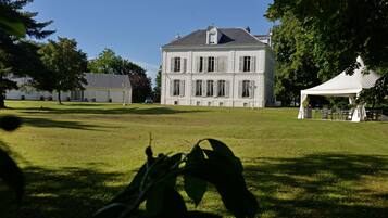 A large, white building with multiple windows and a lawn in front.